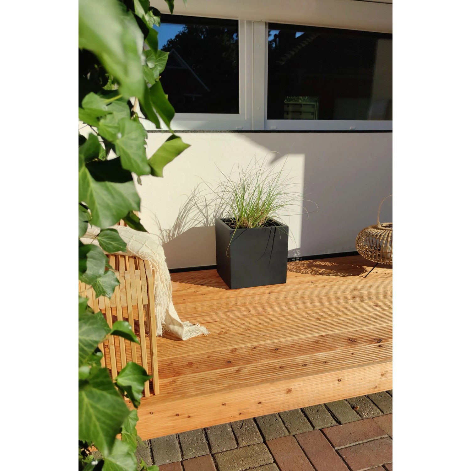 Anthrazitfarbener Vivanno Pflanzkübel Block 40x40x40 cm mit Bepflanzung auf Holzterrasse.
