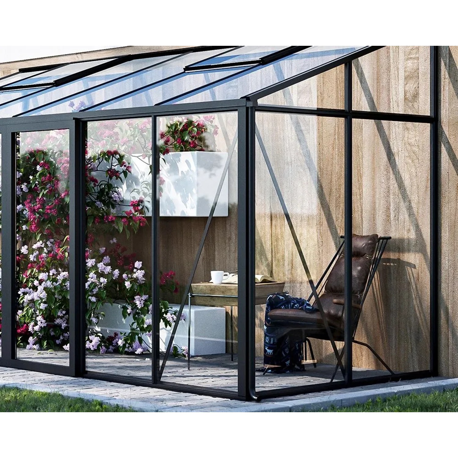 Modernes Bloomcabin Wandgewächshaus mit schwarzem Aluminiumrahmen, Glaswänden, blühenden Pflanzen und Sitzbereich an Holzwand.