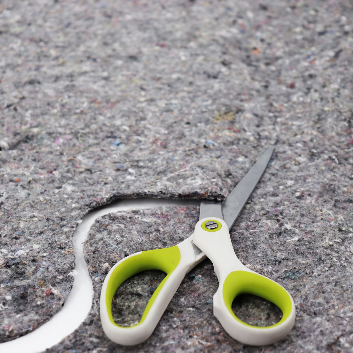 Graues Aquagart Teichvlies 500g wird mit einer Schere zugeschnitten.