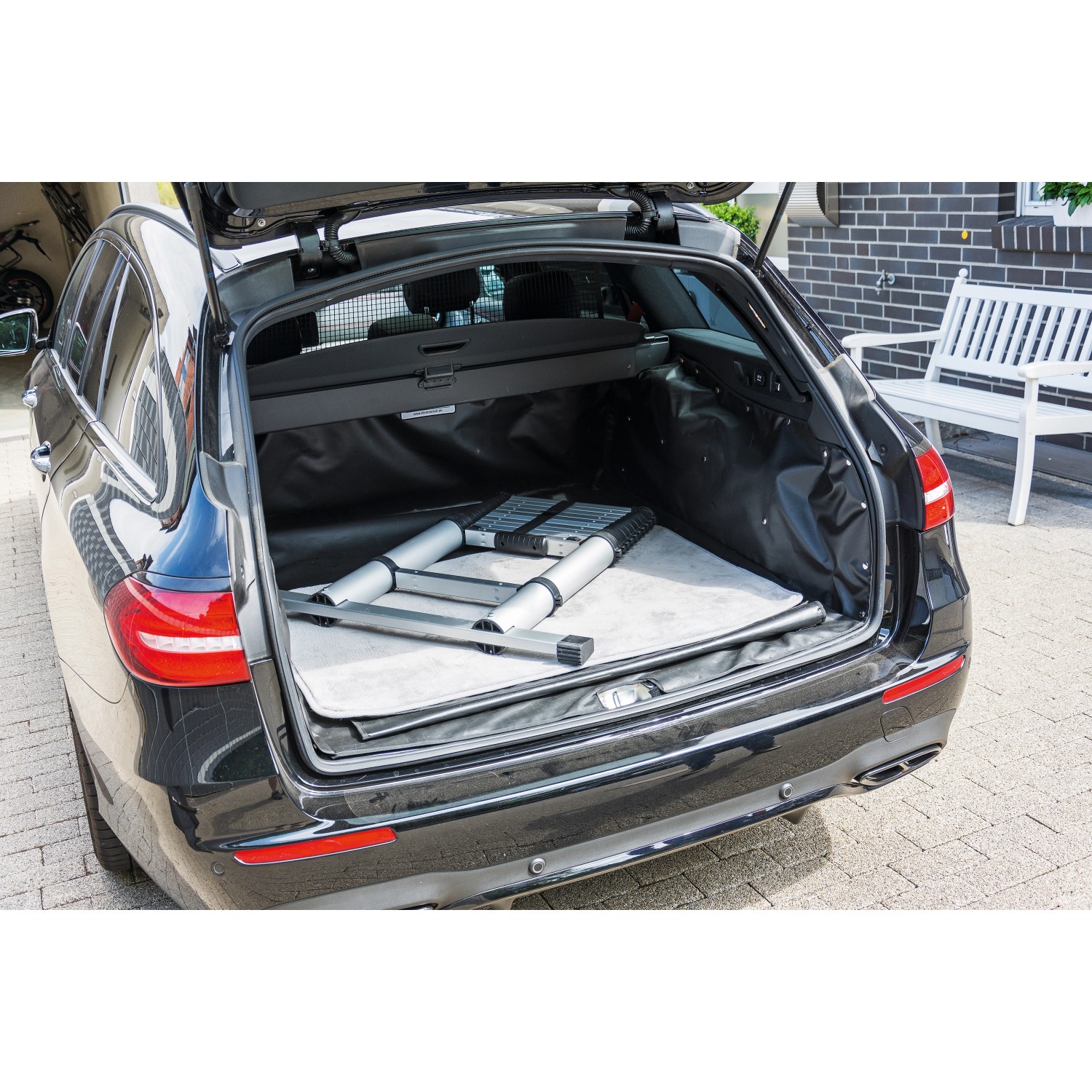 Zusammengeklappte Aluminium Teleskopleiter (11-stufig) im Kofferraum eines Autos.