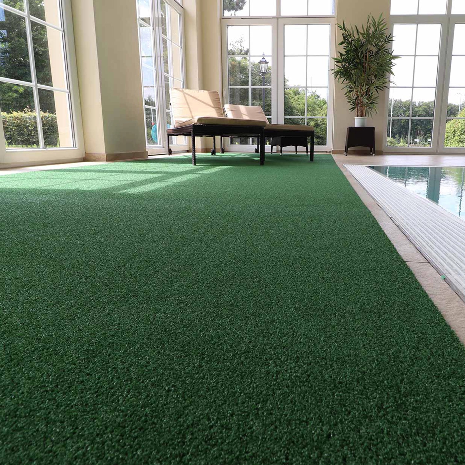 Grüner Primaflor Kunstrasen Summer B1 im Innenraum neben einem Pool.