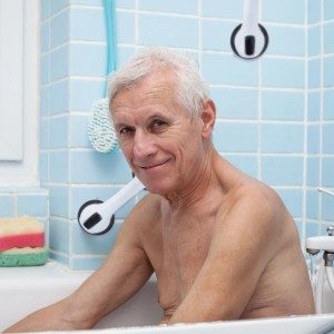 Senior in Badewanne nutzt weißen Haltegriff mit Saugnapf an blauer Wand. Bietet Sicherheit und Unterstützung im Bad.