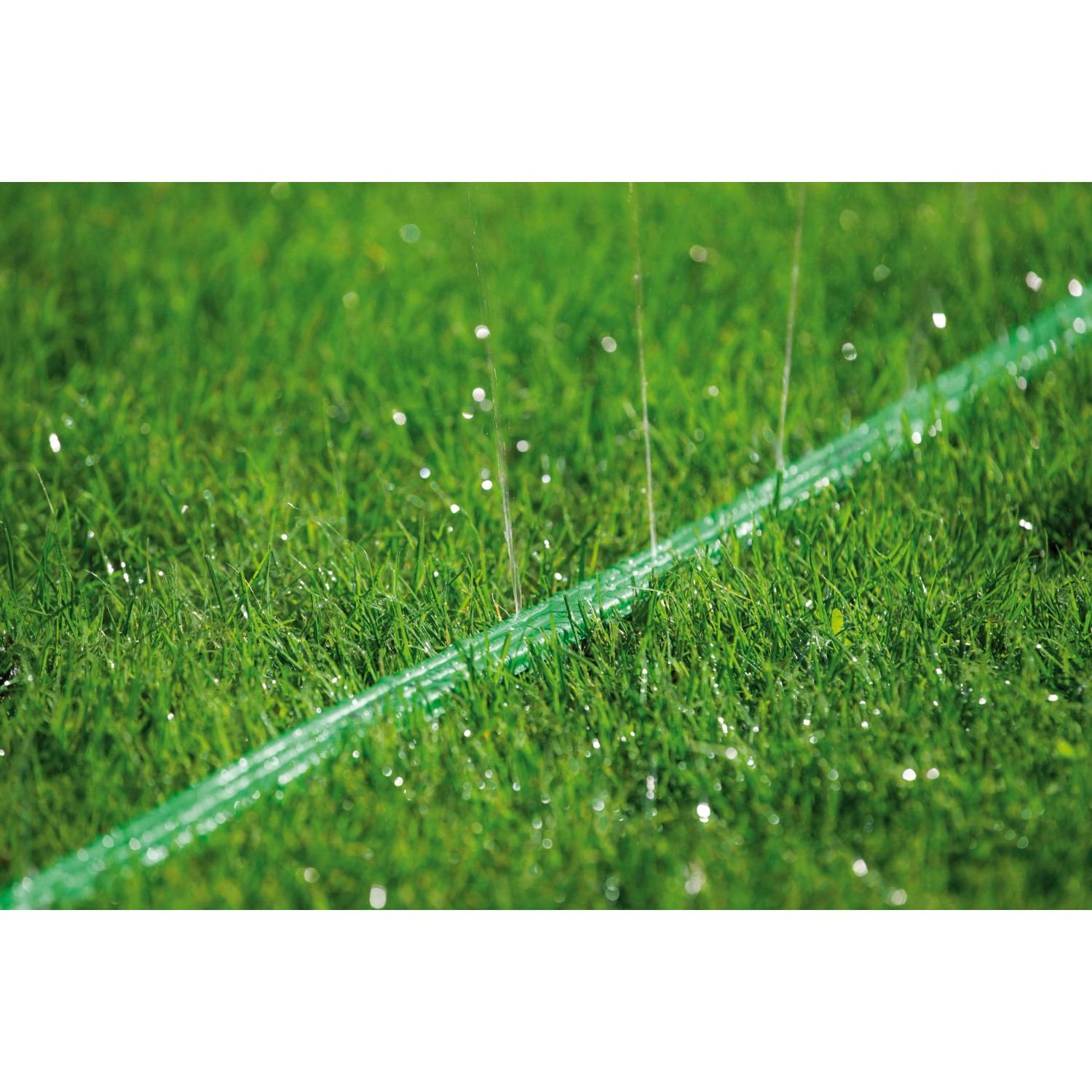 Grüner Gardena Schlauch-Regner 15m im Einsatz auf Rasen, bewässert schmale Gartenbereiche.