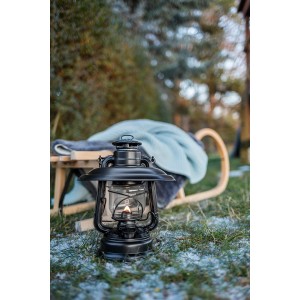 Feuerhand Sturmlaterne Baby Special mit Reflektorschirm, mattschwarz, auf winterlicher Wiese.