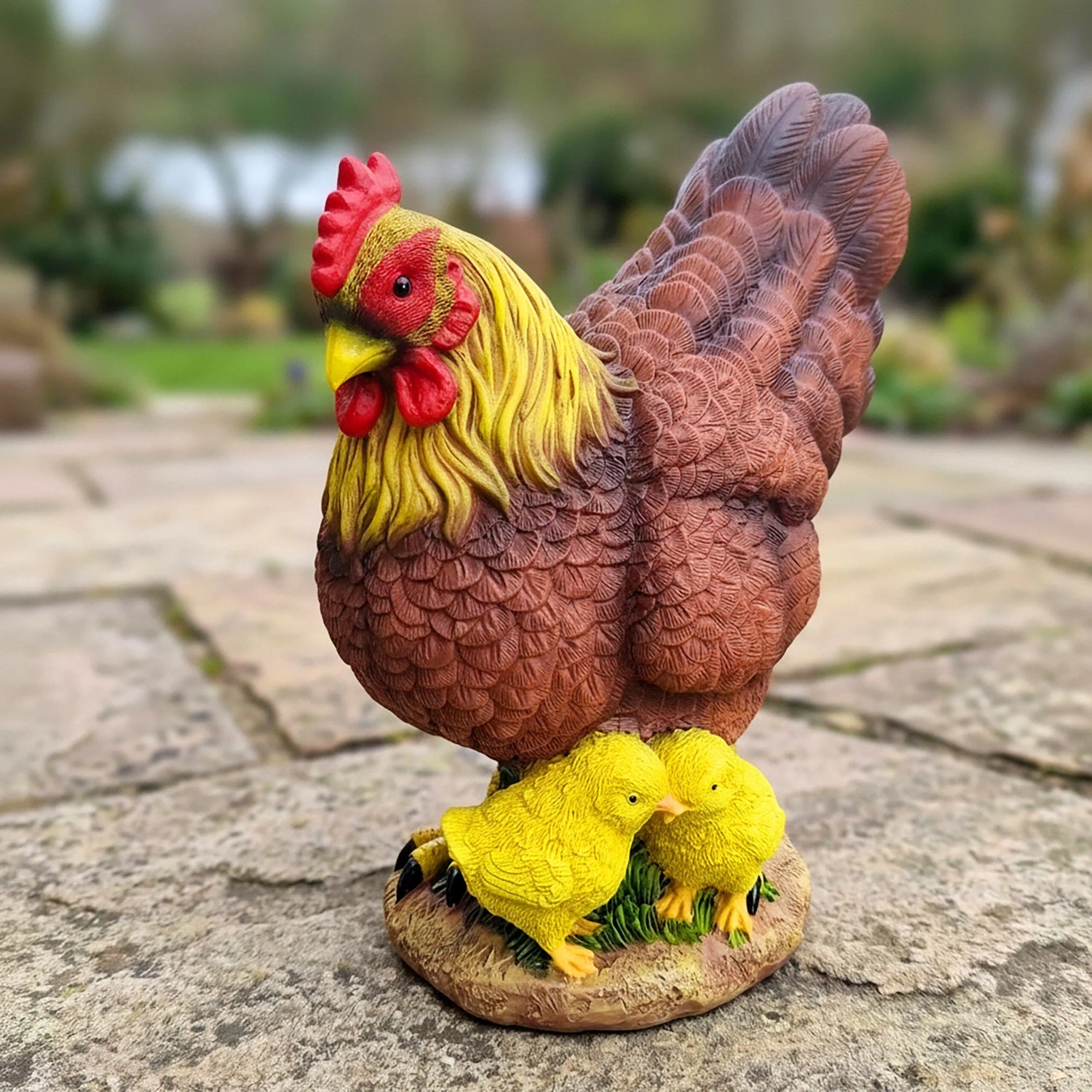 Bunte Gartenfigur Huhn mit zwei gelben Küken aus Polyresin für ländliche Gartendekoration.