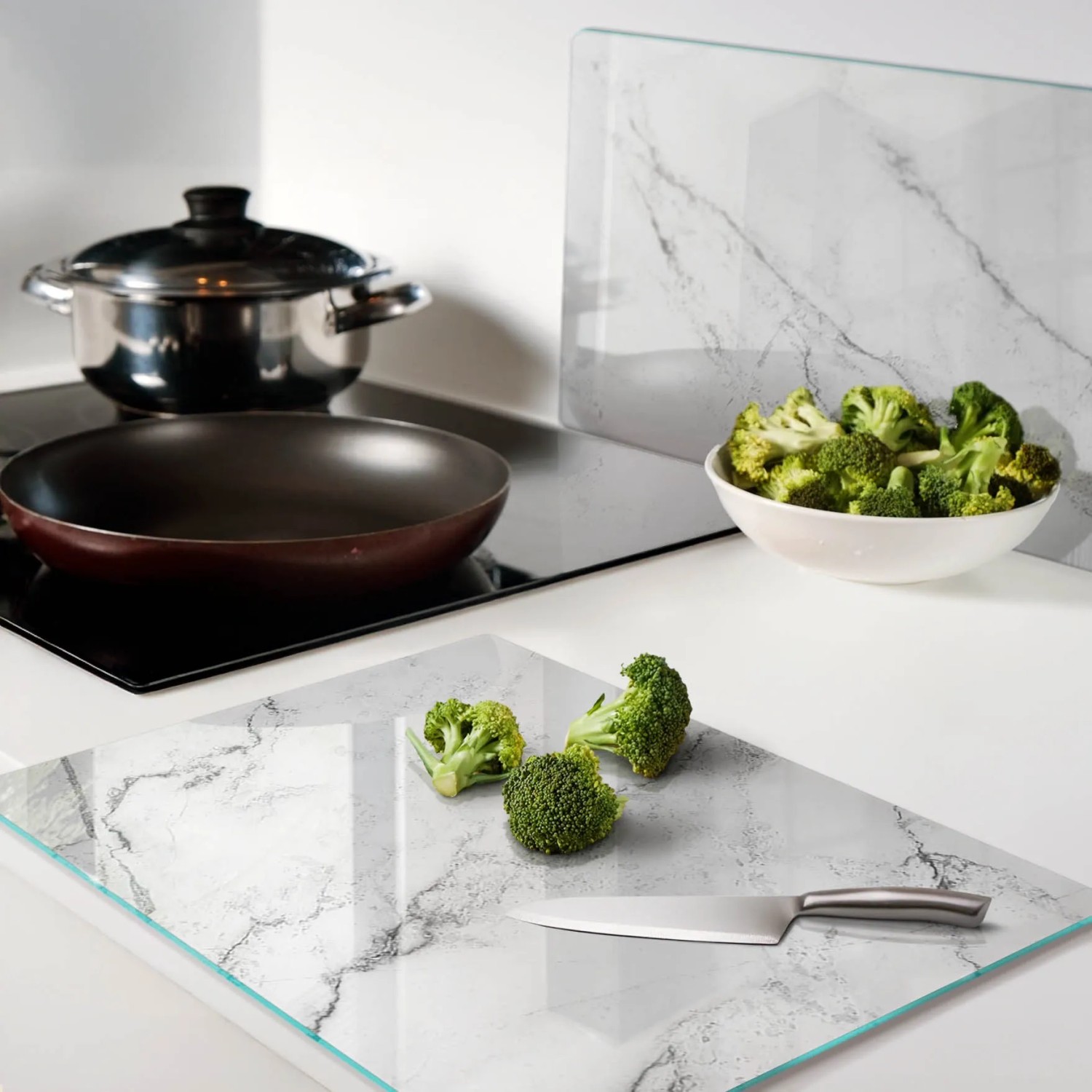 Zwei Tulup Glas-Herdabdeckplatten mit Marmor-Design in Küche. Eine als Schneidebrett, eine als Spritzschutz. Kratzfest, hitzebeständig.
