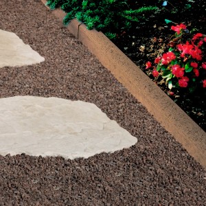 Abgerundeter, brauner Kann Rasenkantenstein aus Beton (30x100x5 cm) als Beetbegrenzung im Garten.