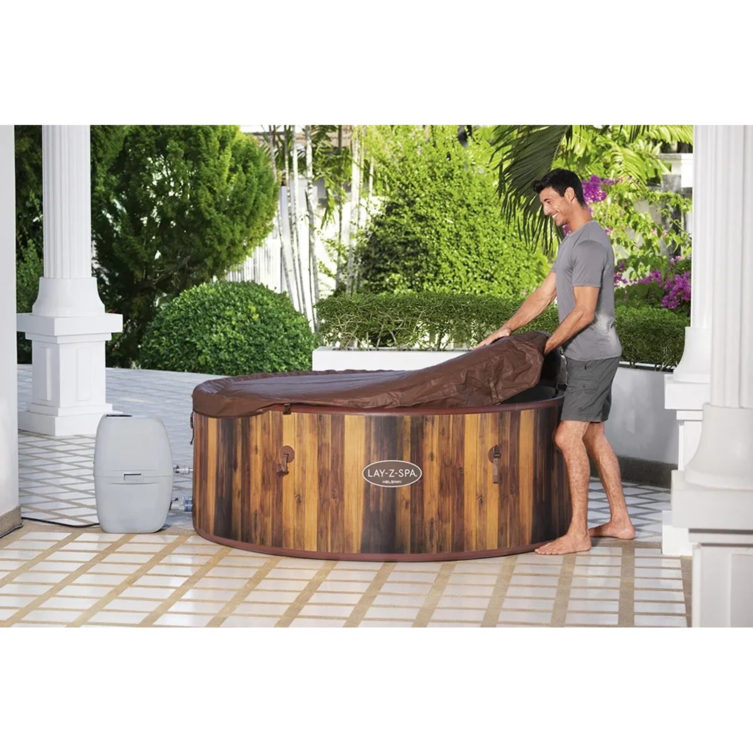 LAY-Z-SPA Helsinki AirJet Whirlpool mit Abdeckung und Mann im Garten.
