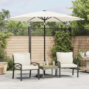 Großer weißer Sonnenschirm mit Strohfransen und schwarzem Stahlmast auf einer Terrasse mit Sitzgruppe.