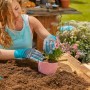 Frau pflanzt Blume mit Gardena Gartenhandschuhen 9/L. Gartenbekleidung für sicheres Arbeiten.