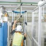 Zarges Teleskop-Plattformleiter ZAP Masterflex Plus mit Mann auf Stufen in Produktionshalle.