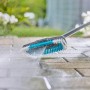 Gardena Cleansystem Stielbürste Hard in Aktion: Reinigung von Pflastersteinen mit Wasser.