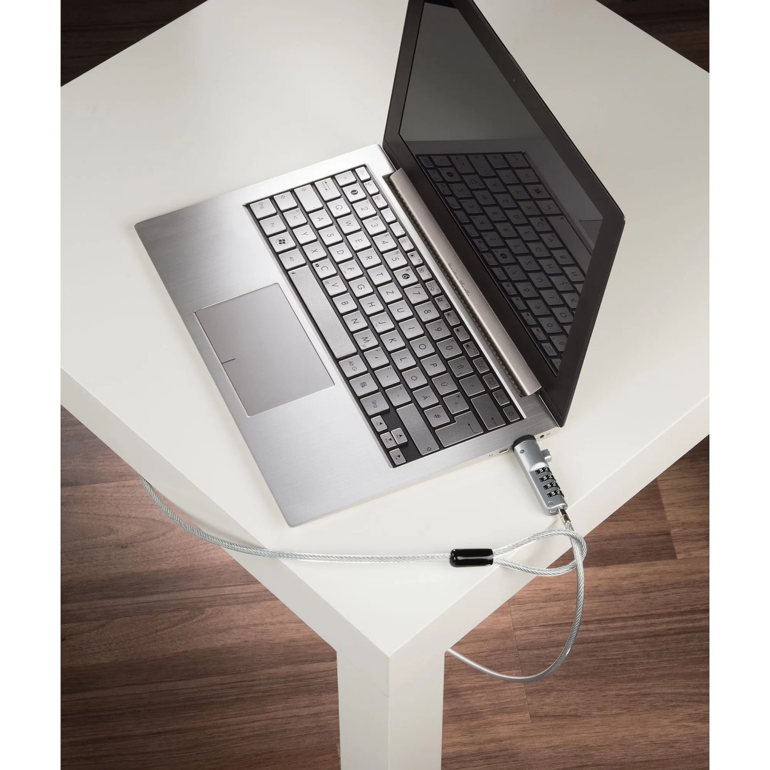 Silbernes Hama Laptopschloss mit Zahlencode am Notebook auf weißem Tisch befestigt.