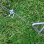 Tepro Verankerungs-Set für Gewächshaus mit Haken und Stahlseil im Grasboden.