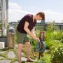 Mann benutzt Gardena Terrassen-Spiralschlauch 7,5 m zum Bewässern auf einer Dachterrasse.