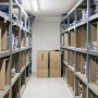 Werkstattregal aus verzinktem Metall mit MDF-Platten, beladen mit Kartons und Waren.