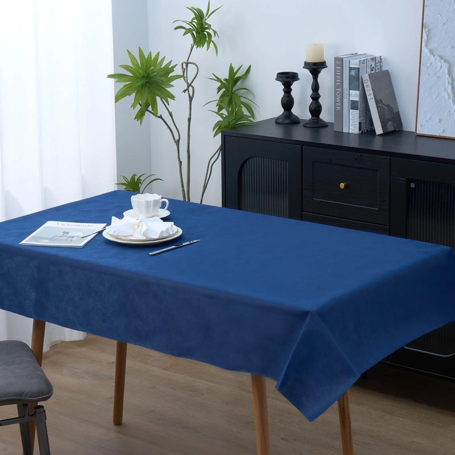 Blaue Vlies-Tischdecke auf Holztisch, gedeckt mit Geschirr. Ideal für Feste und Dekoration.