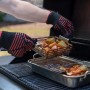Char-Broil Grill+ Körbe (2 Stk.) mit Gemüse auf Grill, gehalten mit Grillhandschuhen.