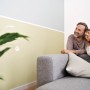 Paar entspannt auf Sofa vor Wand mit Tesa Malerband abgeklebt. Präzise Farbkante.