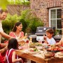 Familie grillt mit Weber Gasgrill E-310 Spirit 2025 Schwarz im Garten.