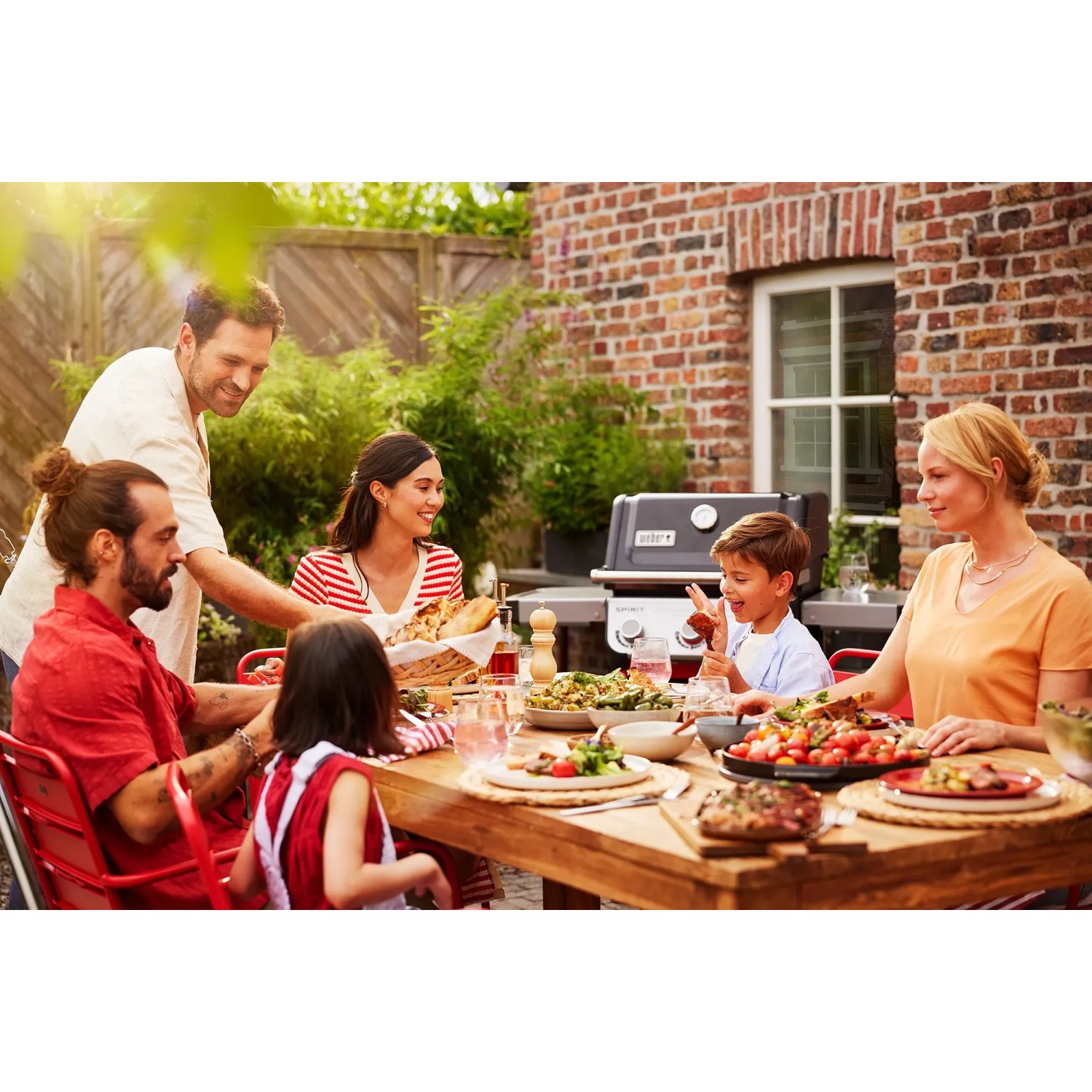 Familie grillt mit Weber Gasgrill E-310 Spirit 2025 Schwarz im Garten.