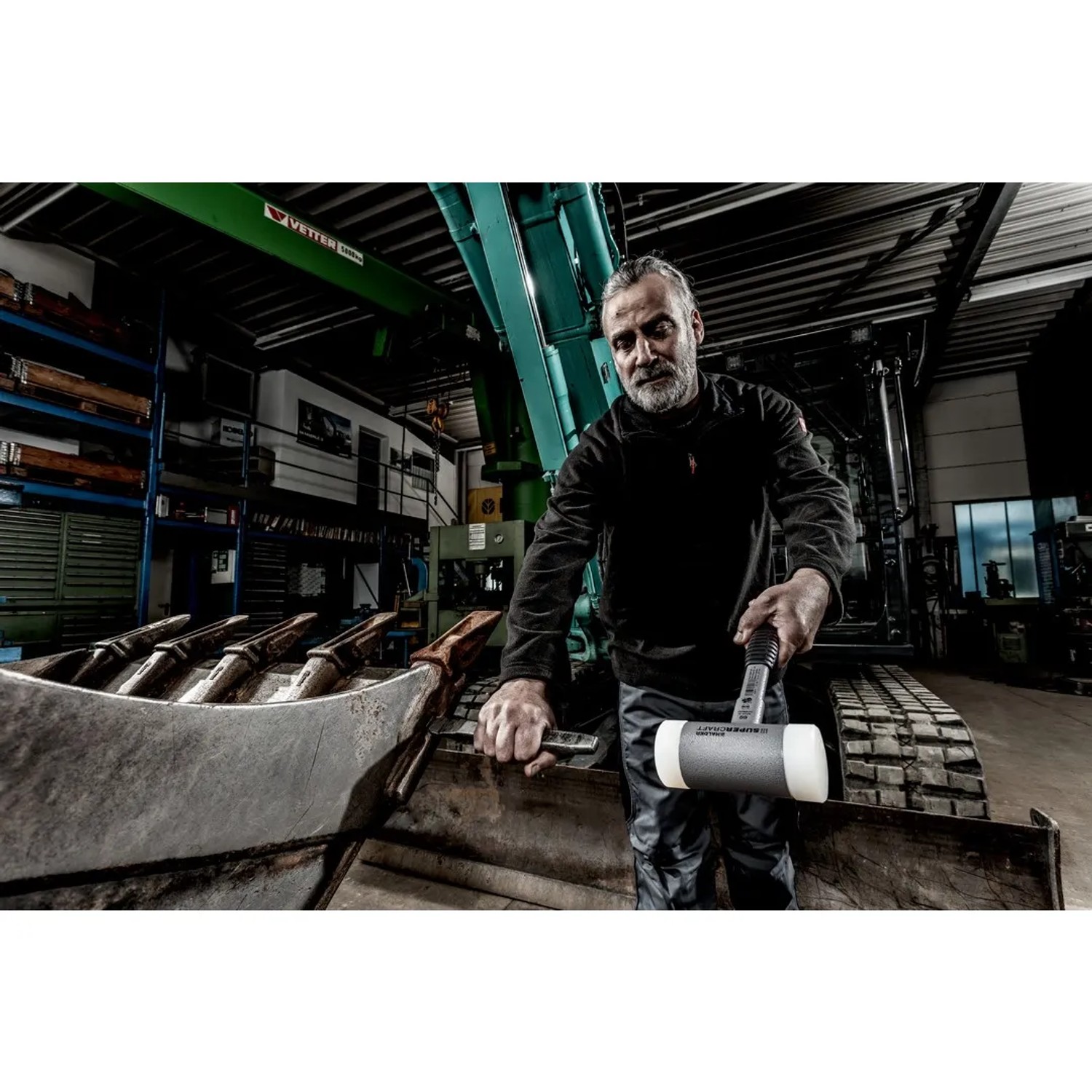 Mann hält Halder Supercraft Schonhammer Ø 45 mm mit Stahlrohrstiel in Werkstatt. Rückschlagfreier Hammer für Montage.