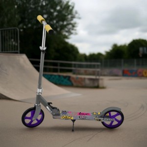 ArtSport Cityroller Graffity Grau mit lila Rädern und gelben Griffen vor Skatepark.