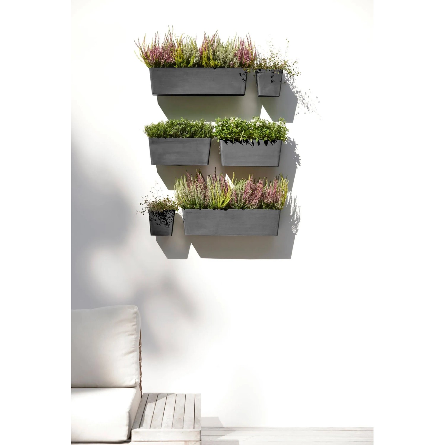 Ecopots Manhattan Wall Hängetöpfe in Dunkelgrau mit Bepflanzung an einer weißen Wand.