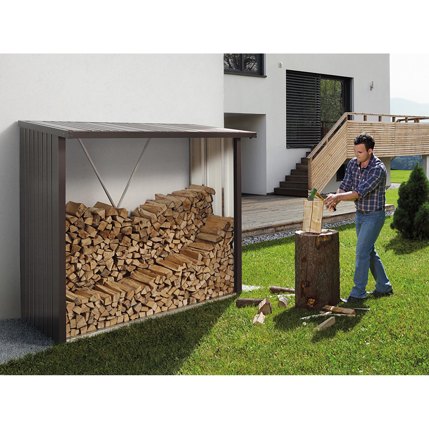 Biohort Kaminholzregal WoodStock 230, quarzgrau-metallic, mit Holzfüllung und Person beim Holzhacken.