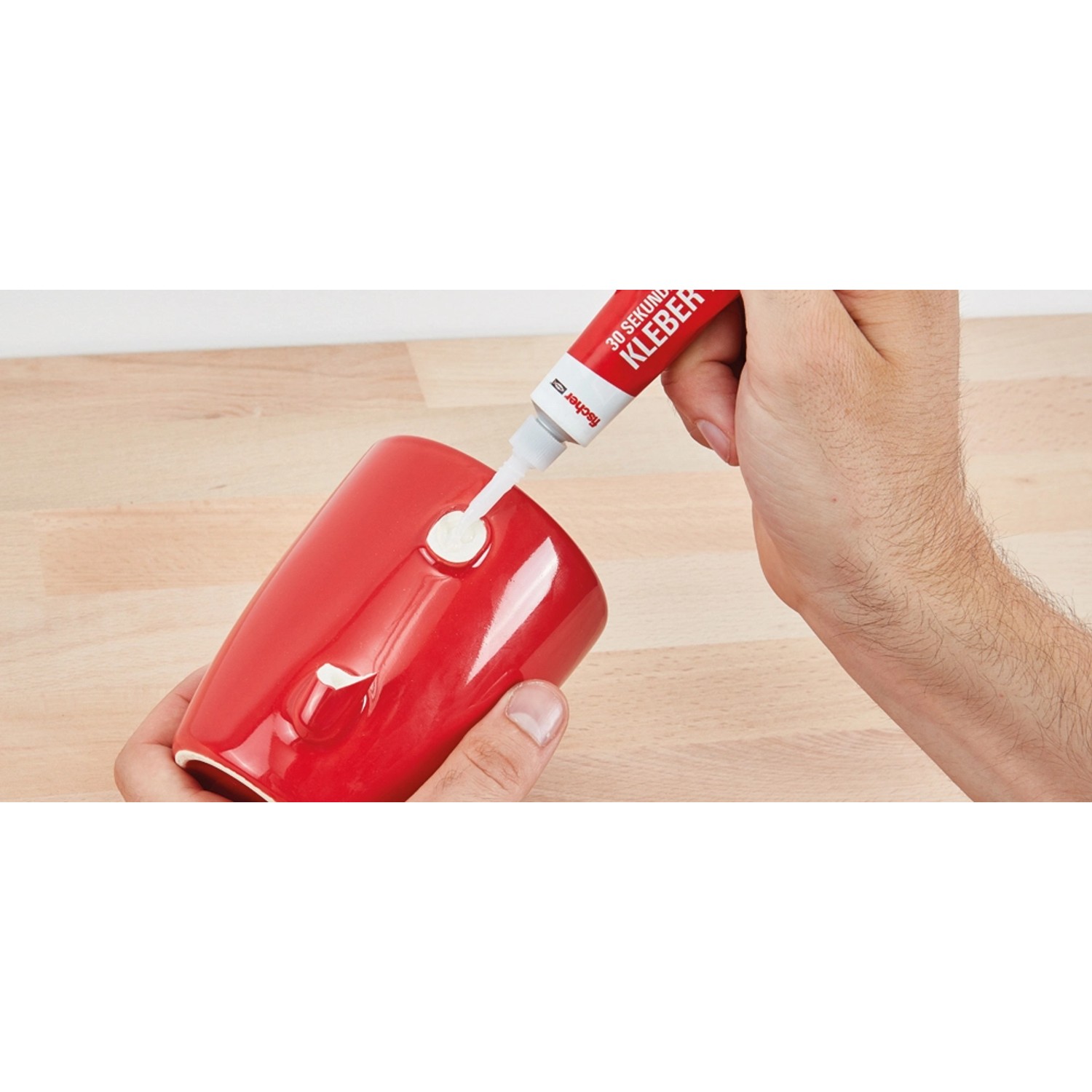Anwendung von Fischer 30 Sekunden Kleber auf einer roten Tasse.