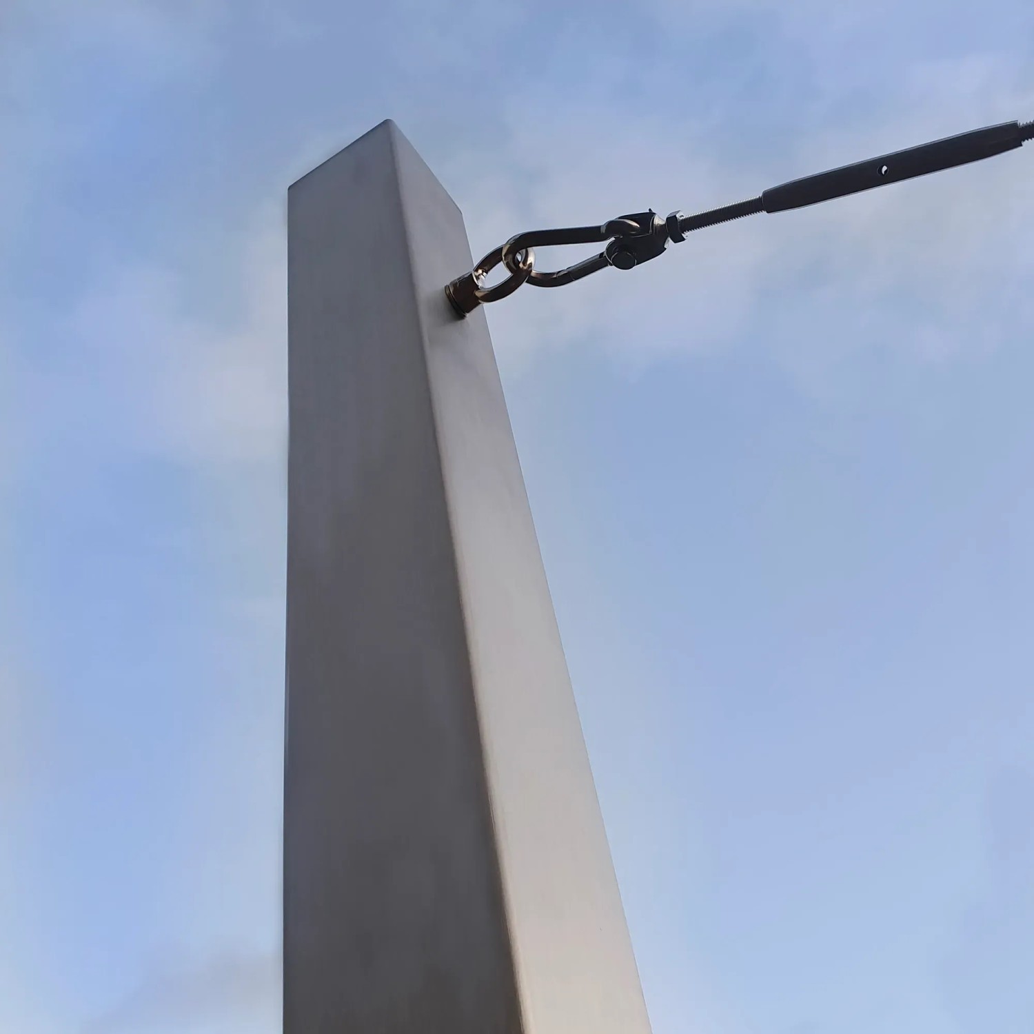 Toldoro Sonnensegelmast aus Edelstahl mit Öse und Spannschloss vor blauem Himmel.