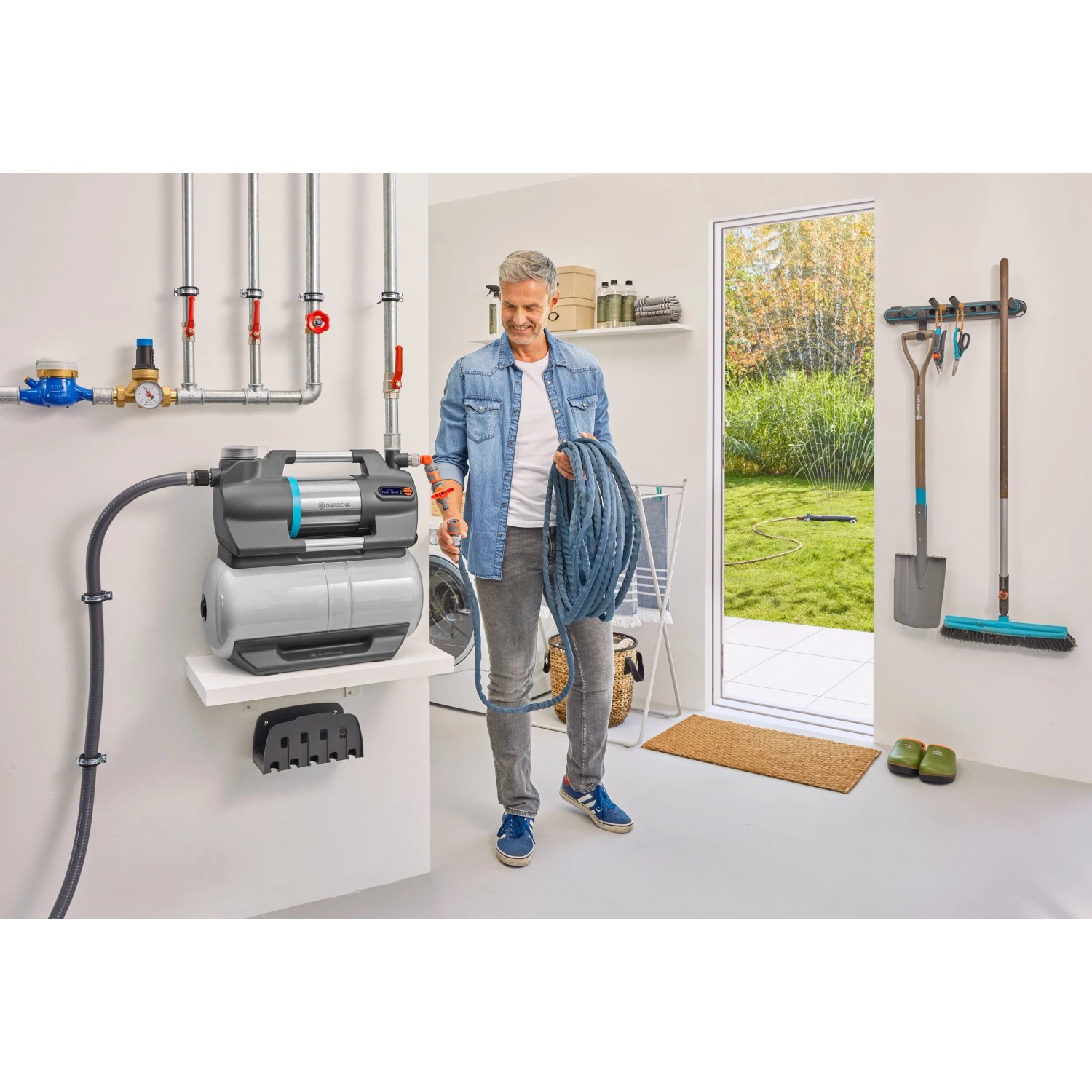 Gardena Hauswasserwerk 5600 SilentComfort mit Schlauch und Anwender in heller Garage.