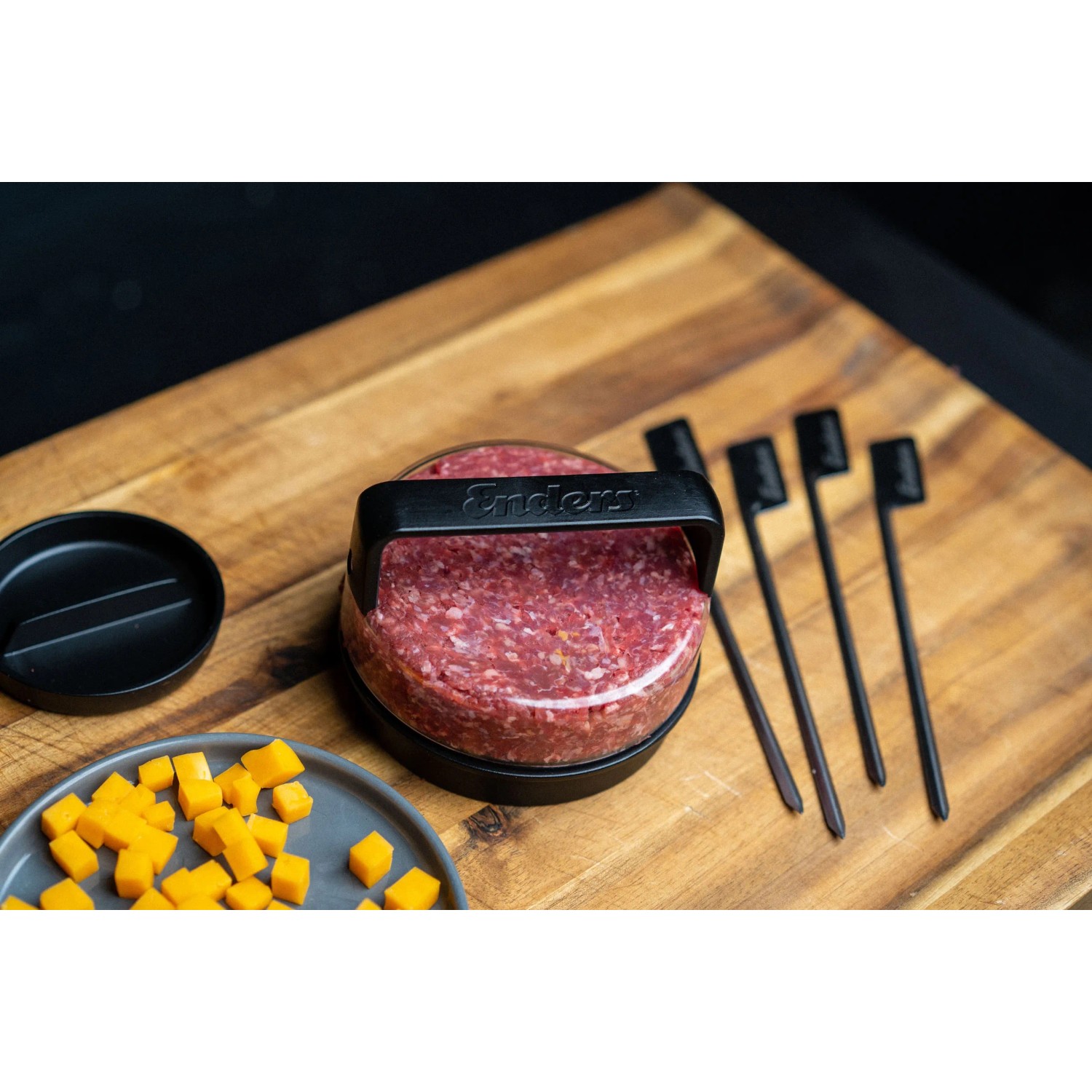 Enders Burgerset Premium: Burgerpresse mit Hackfleisch und Spießen auf Holzbrett.