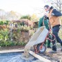Mann schüttet Pfosten- und Fundamentbeton aus Schubkarre in vorbereitete Fläche.