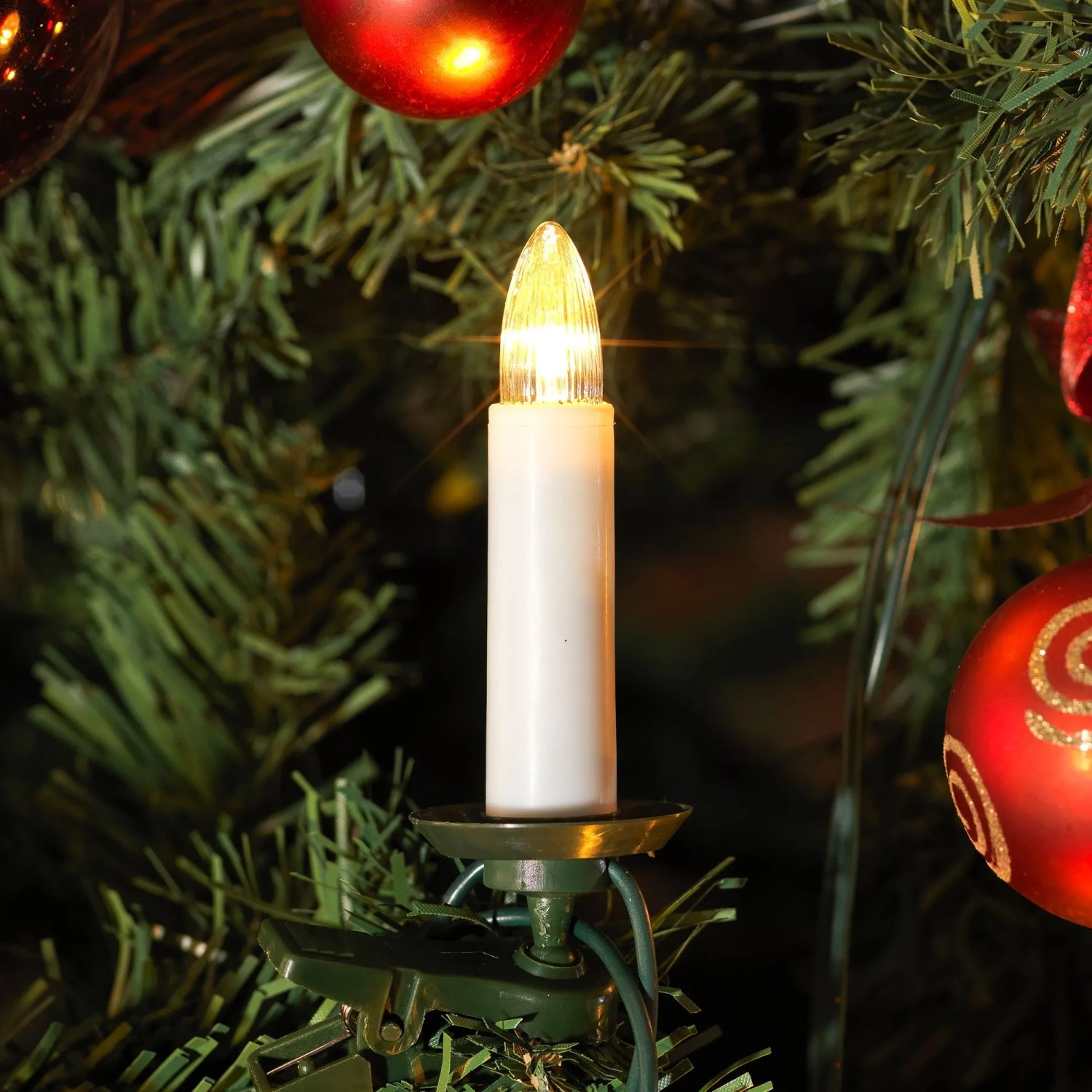 Konstsmide LED-Baumkerze mit grünem Clip am Weihnachtsbaum, warmweiß leuchtend. Für Innen-Lichterketten.