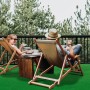 Grüner Primaflor Rasenteppich Park auf Balkon mit entspannten Personen in Liegestühlen.