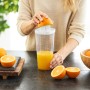 Rotho Küchenhelfer Loft: Frau presst Orange mit dem 5-in-1 Küchengerät, weiß-transparent.