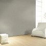 Glööckler Vliestapete Imperial Uni Grau an Wand, kombiniert mit weißem Sessel und Lampe.