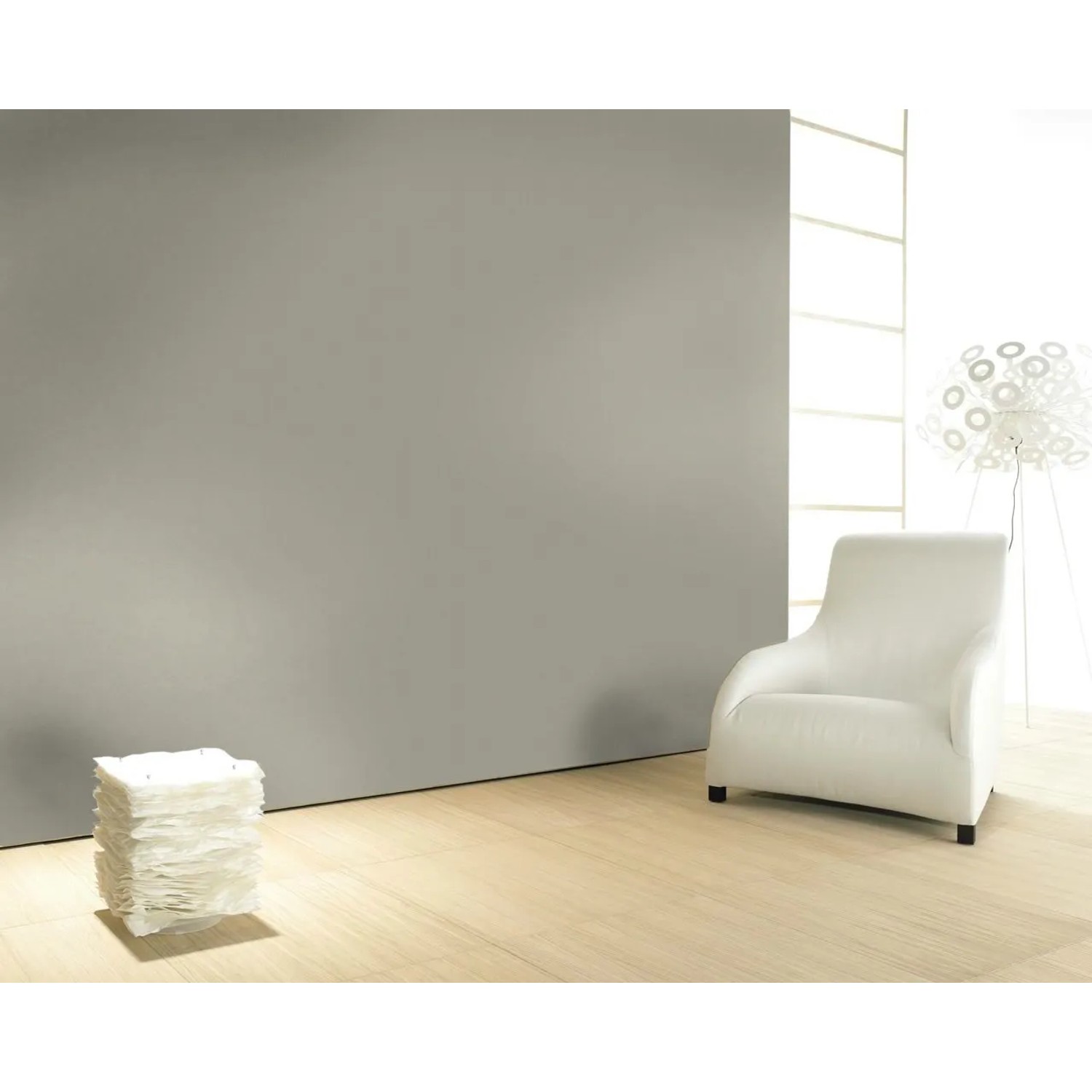 Glööckler Vliestapete Imperial Uni Grau an Wand, kombiniert mit weißem Sessel und Lampe.