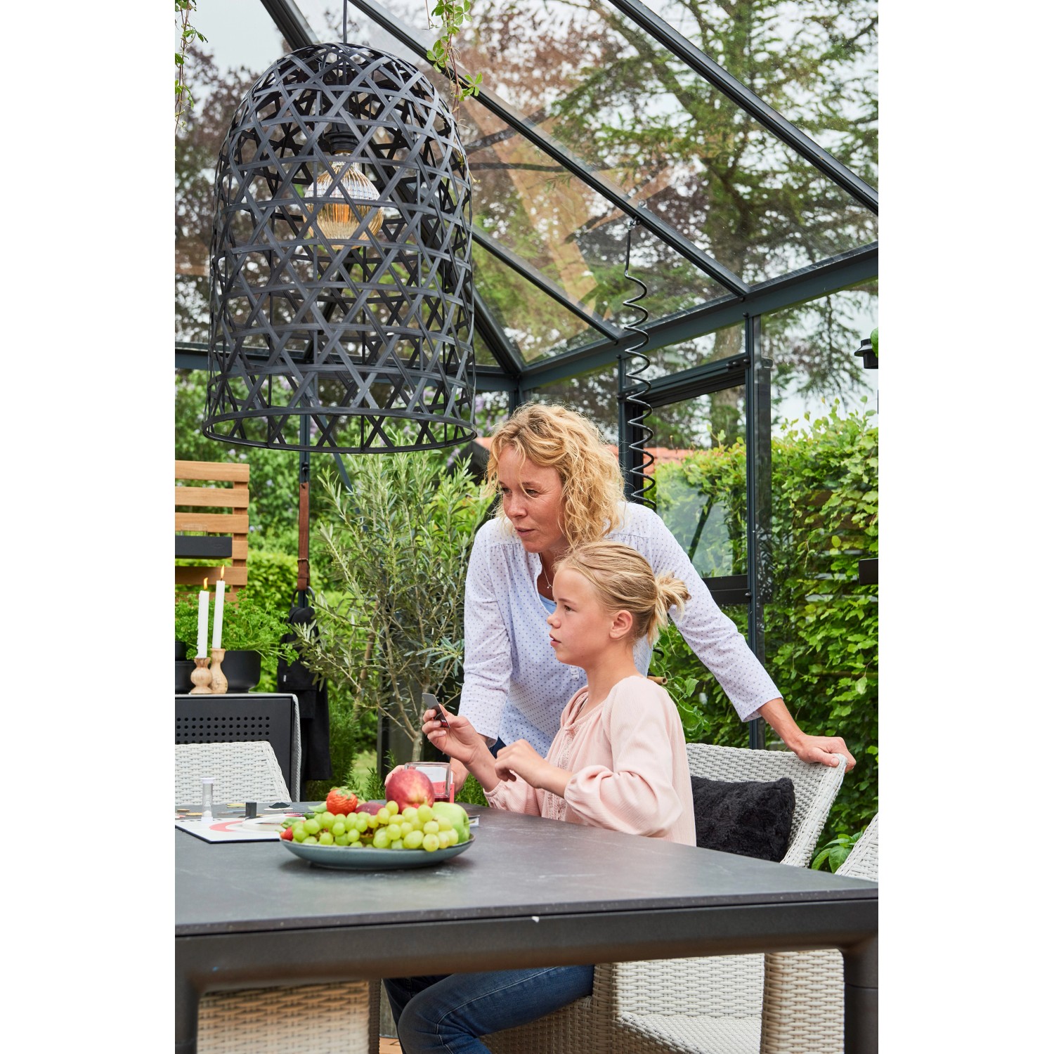 Juliana Gewächshaus Grand Oase 18: Mutter und Tochter am Tisch im Gewächshaus mit Lampe.