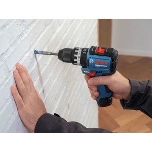 Blaue Bosch PRO Akku-Schlagbohrmaschine GSB12V-31 bohrt präzise in eine weiße Ziegelwand. Ideal für Bohr- und Schraubarbeiten.
