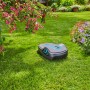 Gardena smart Sileno life Mähroboter Set auf Rasenfläche vor blühenden Büschen.
