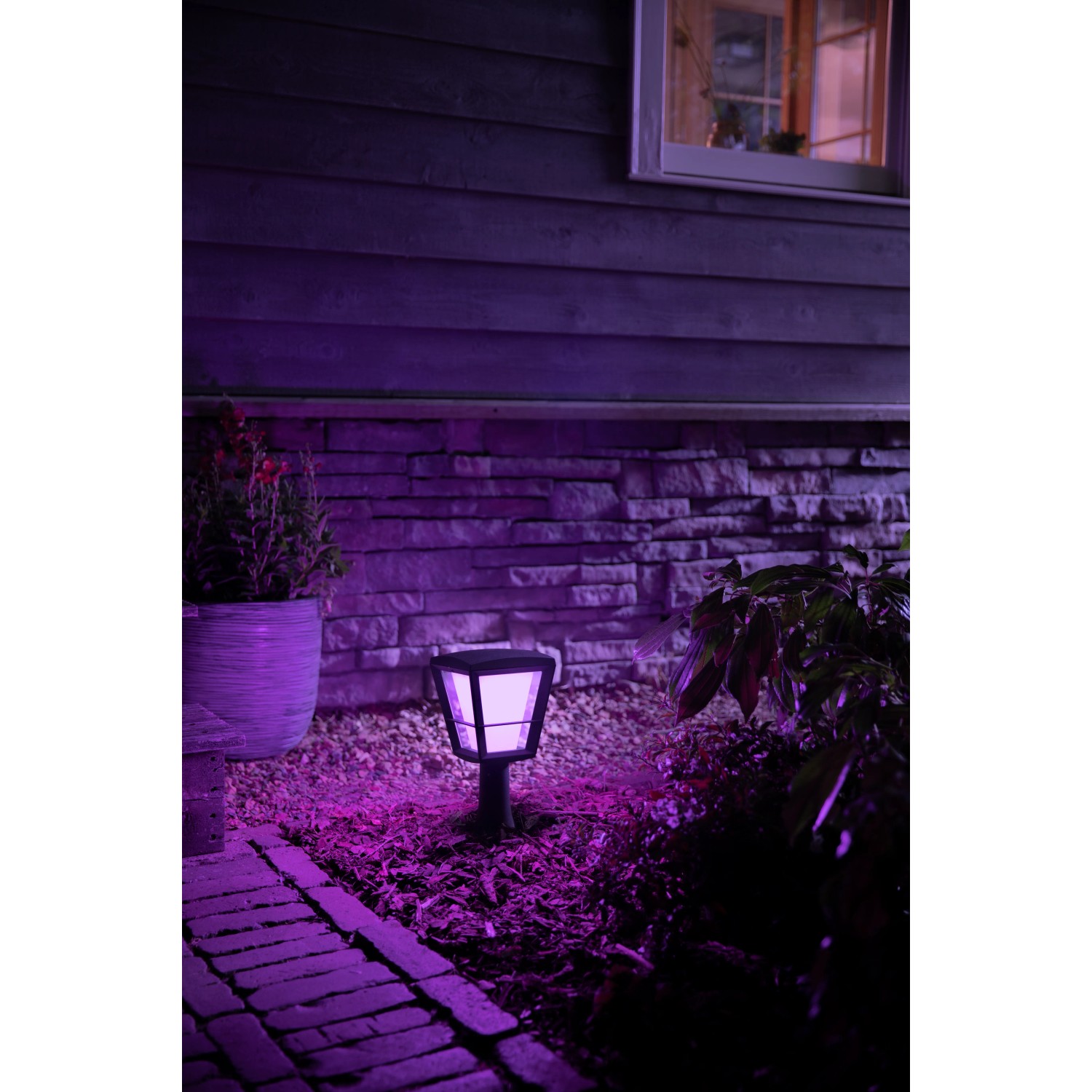 Philips Hue Econic LED Sockelleuchte im Garten mit violetter Beleuchtung.