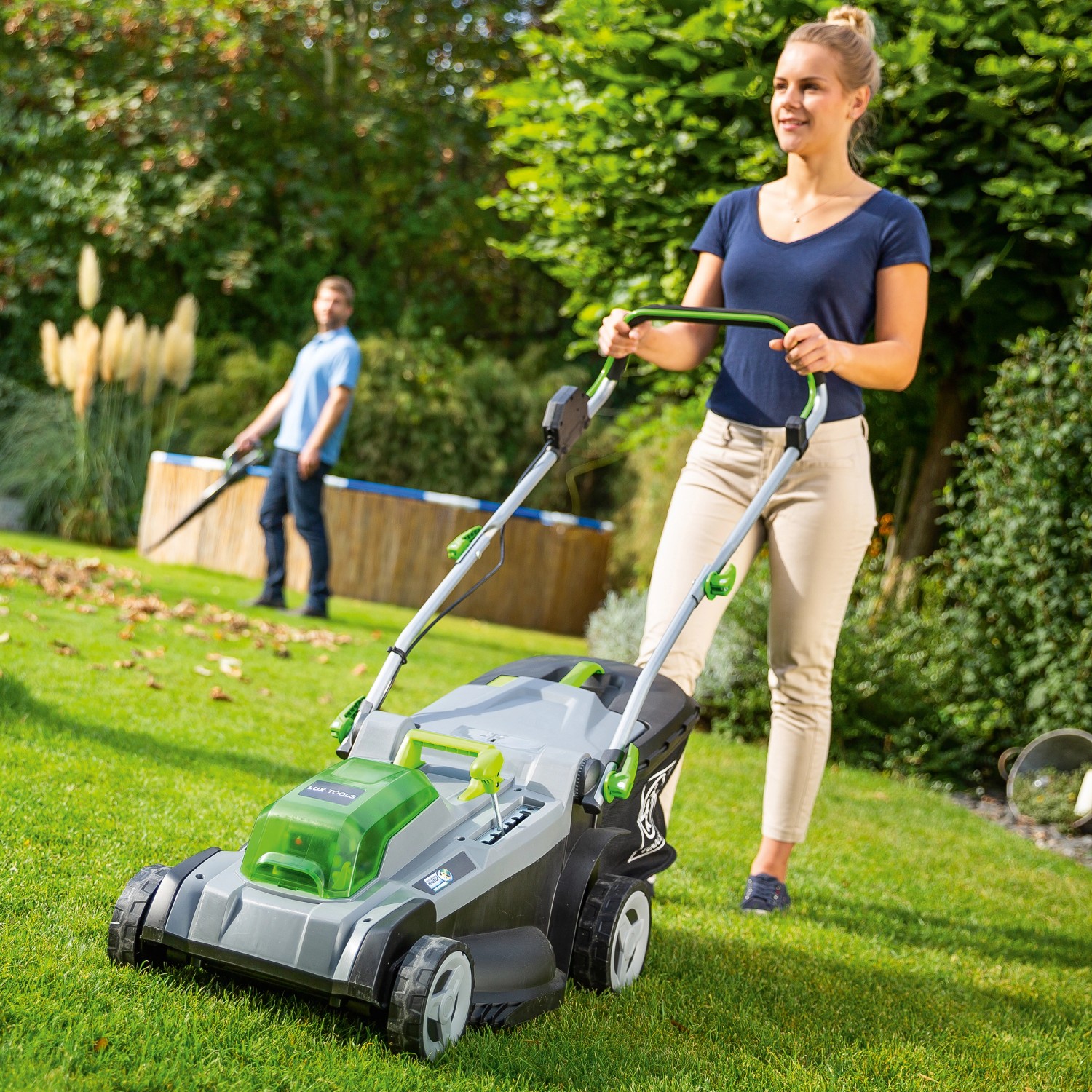 LUX Akku-Rasenmäher 40V im Einsatz: Frau mäht Rasen, Mann im Hintergrund. Ideal für Flächen bis 550 m².