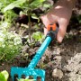 Gardena combisystem-Blumenrechen im Einsatz: Hand lockert Erde mit dem Rechen. Ideal für Garten & Beet.