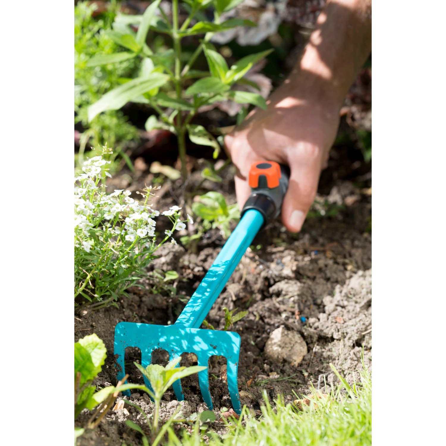 Gardena combisystem-Blumenrechen im Einsatz: Hand lockert Erde mit dem Rechen. Ideal für Garten & Beet.