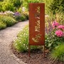 Rostbrauner Gartenstecker aus Eisen mit "Moin Moin" Schriftzug und Anker im Blumenbeet. Wetterfeste Gartendeko.