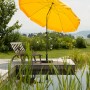 Goldgelber Schneider Balkonschirm Aquila Ø 250 cm mit Knickfunktion auf Terrasse am Wasser.