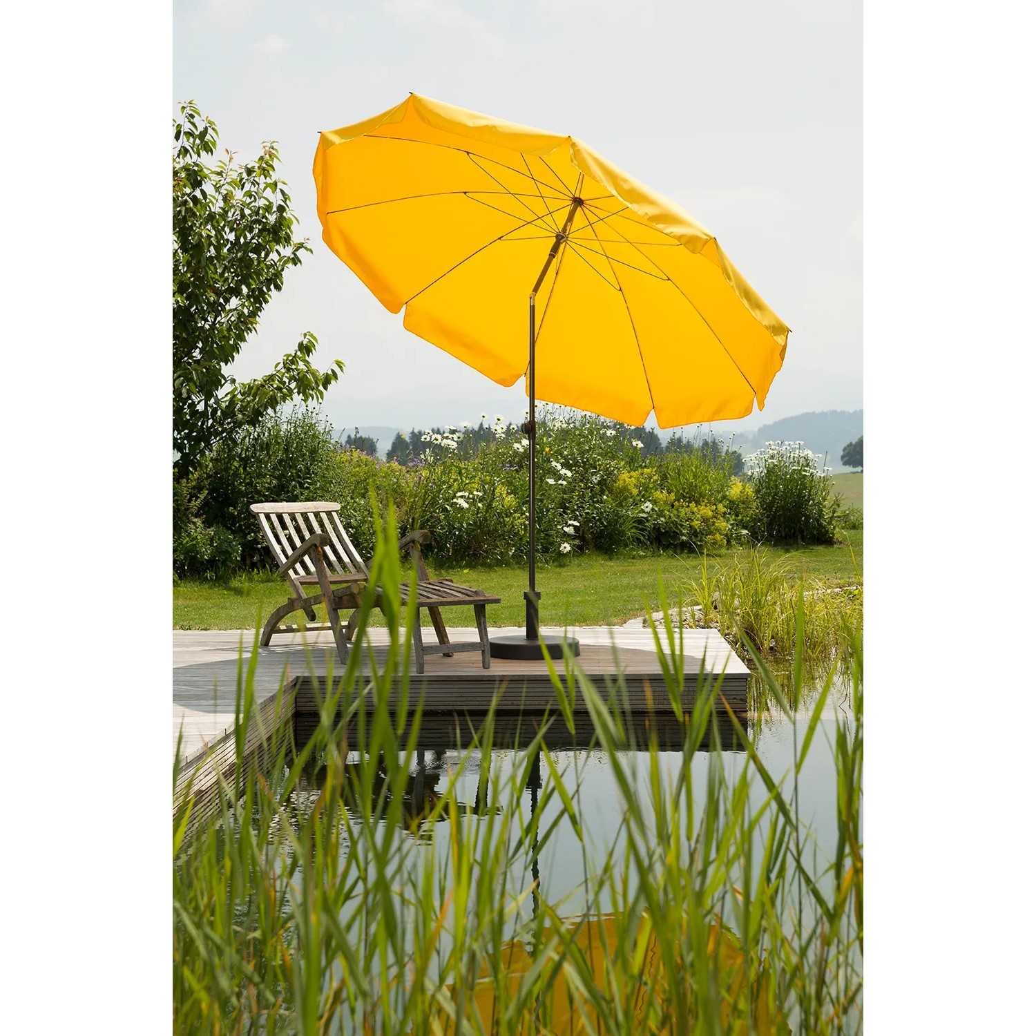 Goldgelber Schneider Balkonschirm Aquila Ø 250 cm mit Knickfunktion auf Terrasse am Wasser.