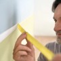 Mann klebt gelbes Tesa Malerband an Wand für präzise Farbkanten.